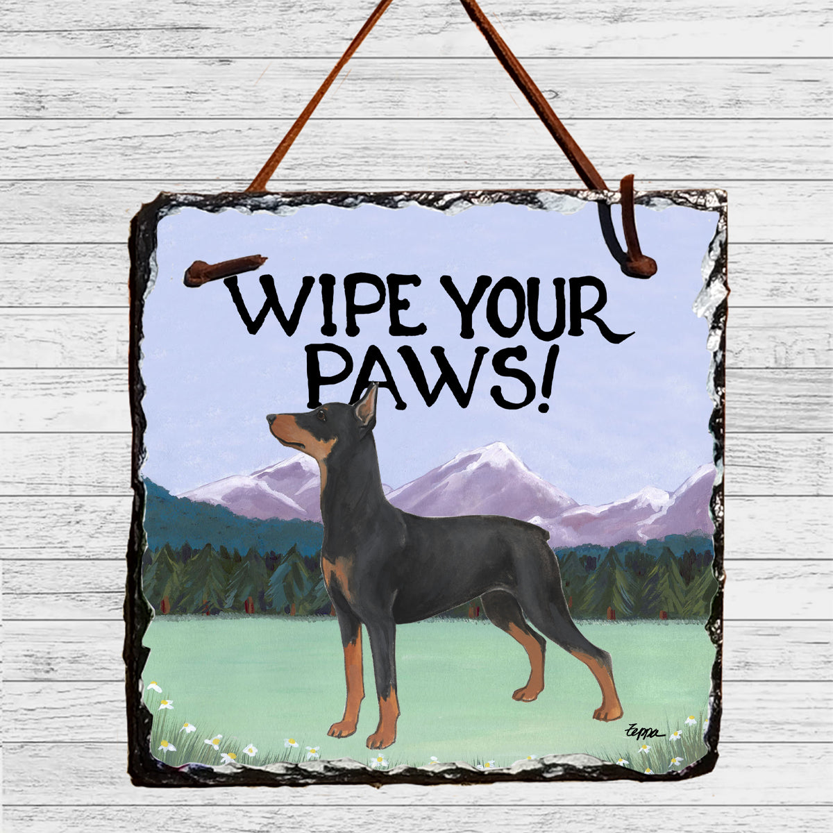 German Pinscher in a scenic mountain setting on a hanging slate sign that says "Wipe Your Paws".