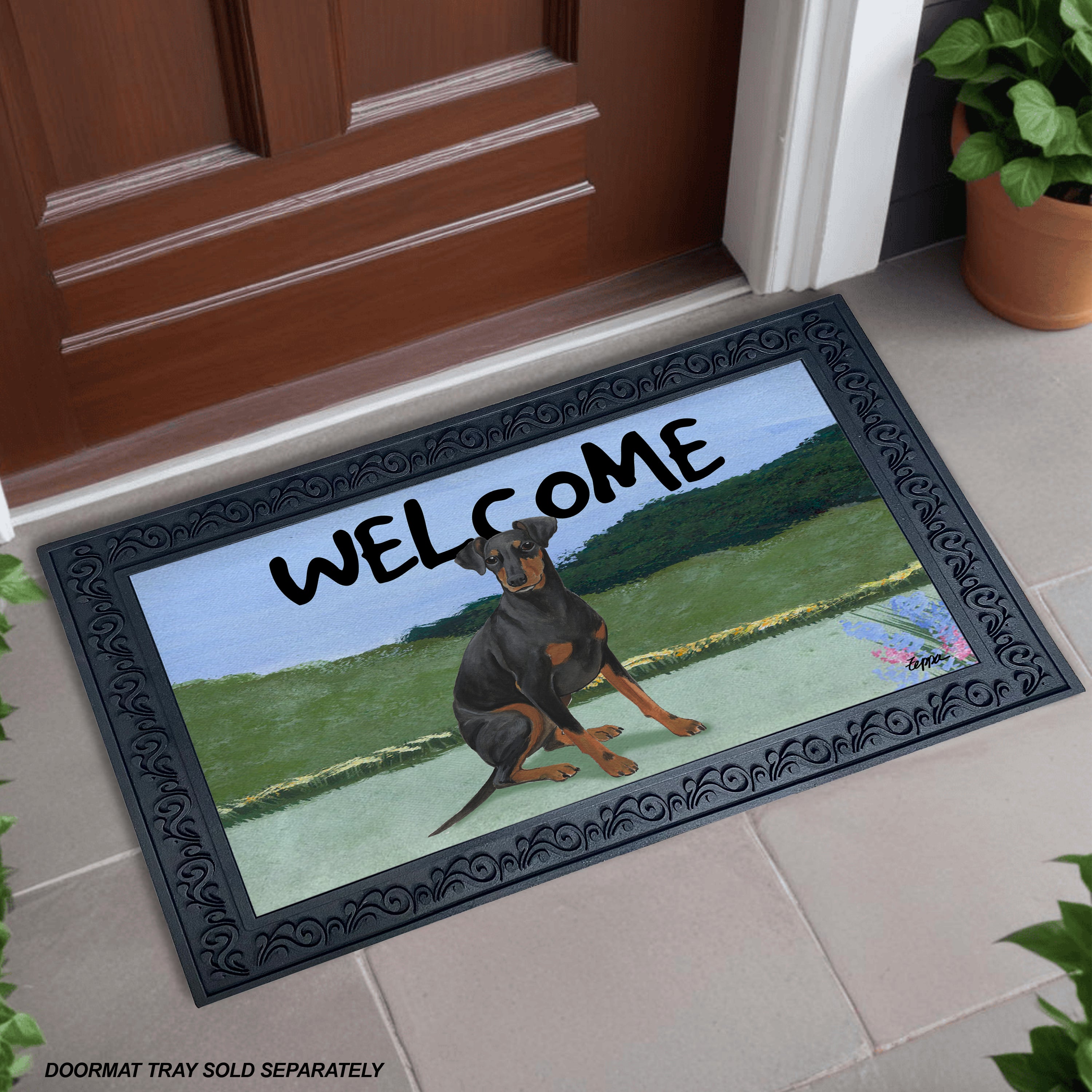 A welcome doormat in a scrolled rubber frame with an illustration of a Manchester Terrier in a yard scene.