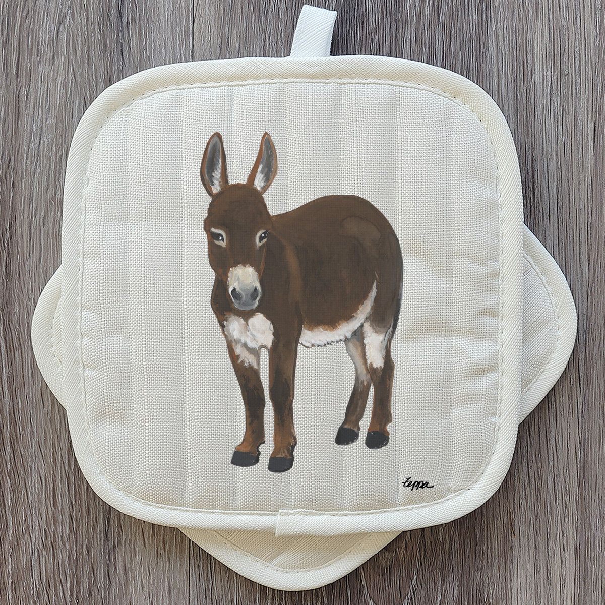 A square cream-colored quilted pot holder set featuring an illustration of a brown mini donkey.