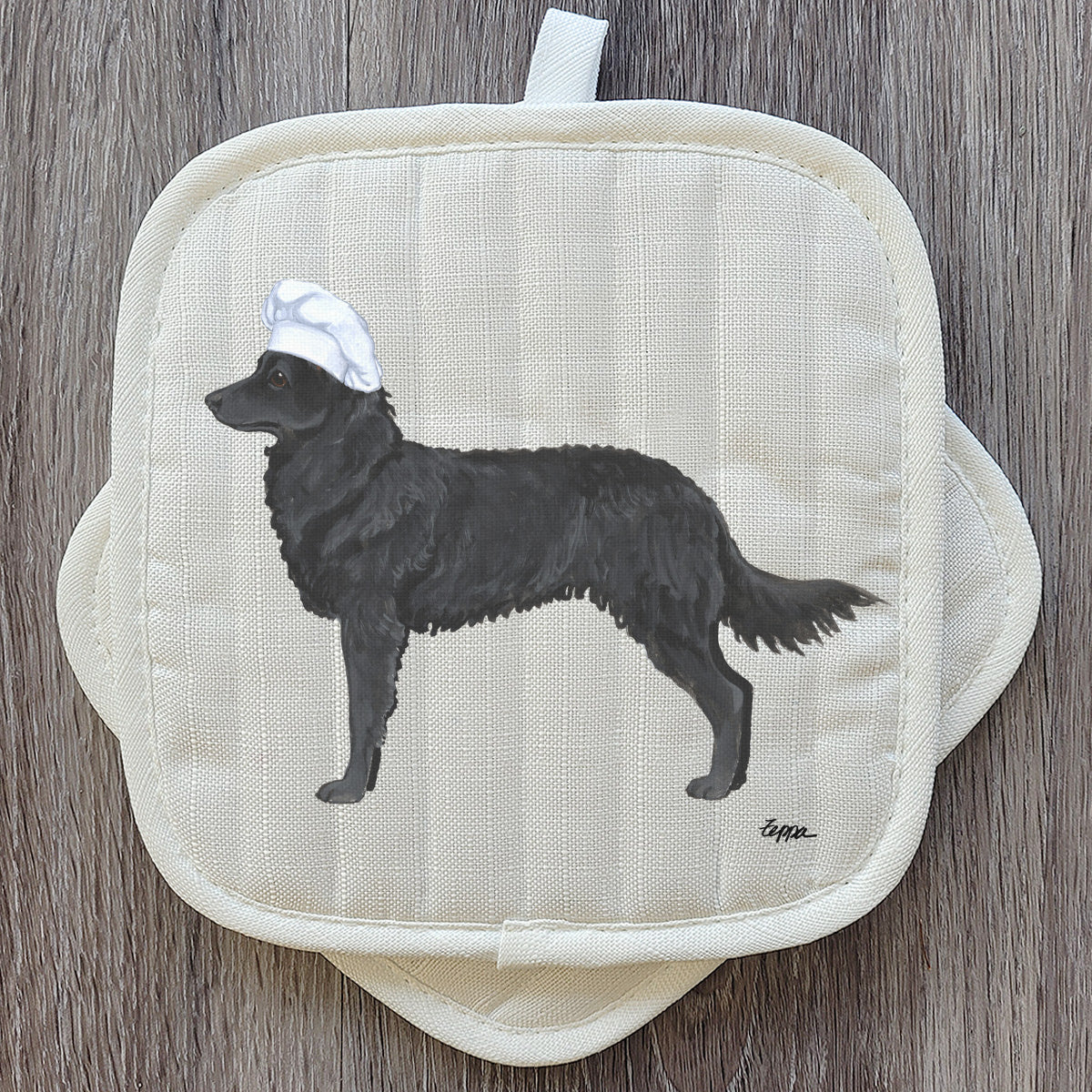 Mudi in a chef's hat on a pair of pot holders.